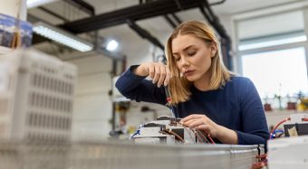 Female electrician working on circuitry in workshop